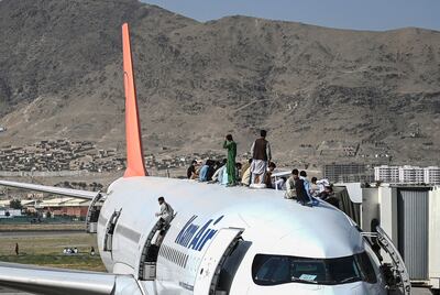 Afghan people climb atop a plane as they wait at Kabul airport. AFP