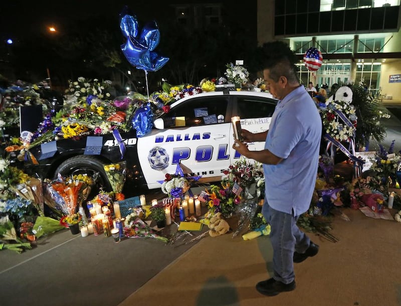 A passerby places a candle on a public memorial outside Dallas police headquarters. Gerald Herbert / AP