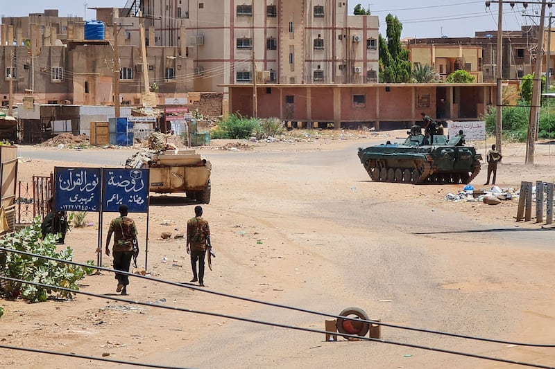Sudanese soldiers walk near armoured vehicles stationed on a street in southern Khartoum. AFP