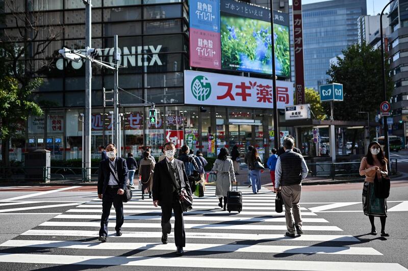People walk on a pedestrian crossing in Tokyo on November 16, 2020, as government data showed Japan's economy exited recession in the third quarter, growing a better-than-expected 5.0 percent following a record contraction.   / AFP / Charly TRIBALLEAU
