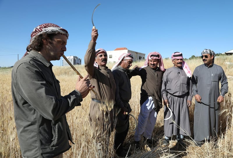 Rabee Zureikat, co-founder of the social enterprise Zikra for Popular Learning, plays an instrument as farmers sing during the wheat harvest in Amman, Jordan. Reuters