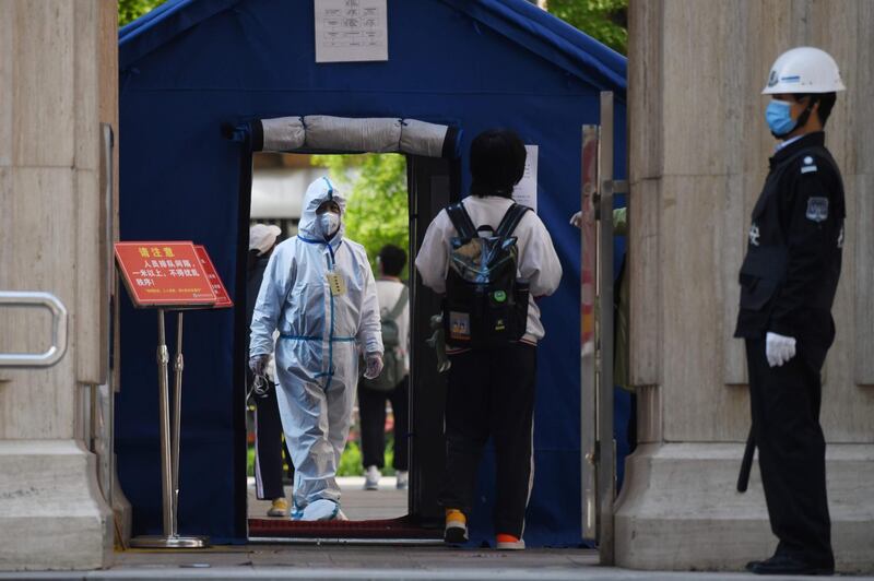 An official in a hazmat suit waits inside a high school entrance as a student arrives in Beijing.  Senior students returned to class for the first time since schools were closed down in January as part of efforts to stop the spread of the COVID-19 coronavirus.   AFP