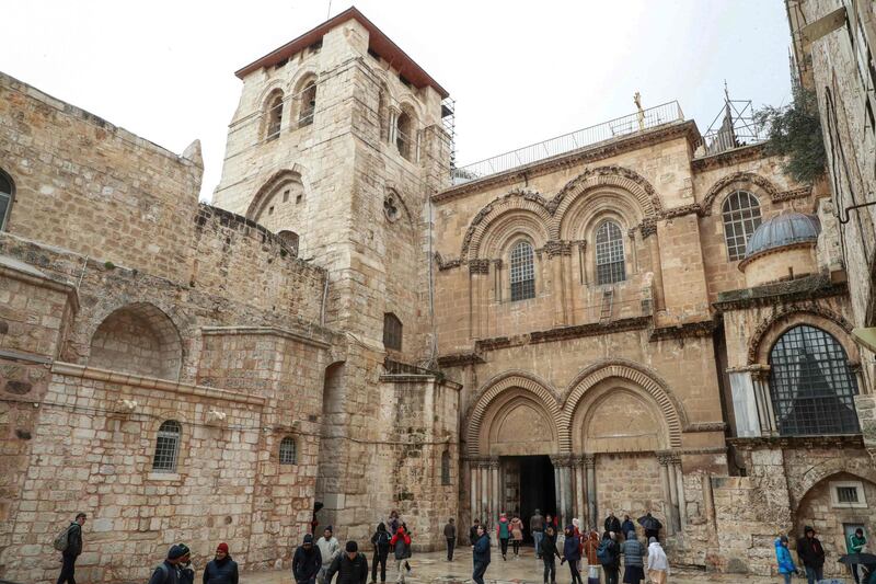People walk outside the Church of the Holy Sepulchre in the Old City of Jerusalem on January 21, 2020.  / AFP / Ludovic MARIN
