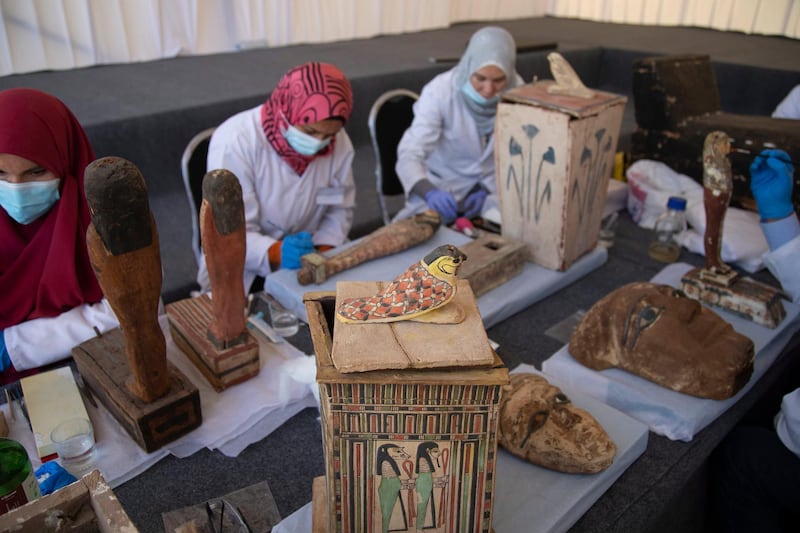 Archaeologists work on artefacts as sarcophaguses are presented to the media near the newly discovered burial site at Saqqara Necropolis in Giza. EPA