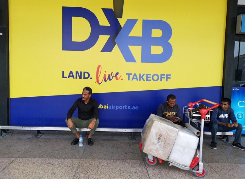 Passengers sit next to a new logo of Dubai Airport, at the departure hall of terminal one, Dubai, United Arab Emirates, July 23, 2019. Picture taken July 23, 2019. REUTERS/Hamad I Mohammed