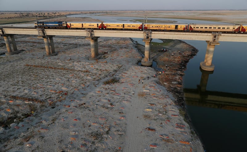 Several bodies are seen buried in shallow graves on the banks of Ganges river in Prayagraj, India. Saturday, May 15, 2021. Police are reaching out to villagers in northern India to investigate the recovery of bodies buried in shallow sand graves or washing up on the Ganges River banks, prompting speculation on social media that they were the remains of COVID-19 victims. (AP Photo/Rajesh Kumar Singh)