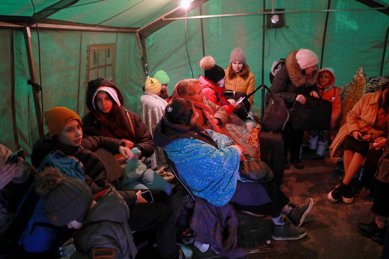 Refugees warm up in a tent after crossing the border in Palanca, Moldova. AP