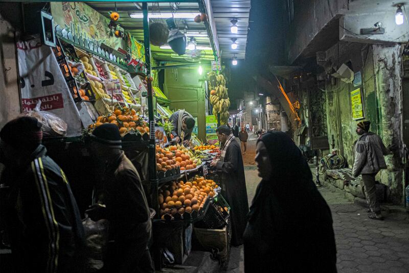 People walk past a fruit seller's stall in the Azhar district of Cairo. AFP