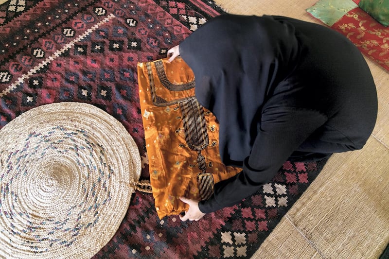 ABU DHABI, UNITED ARAB EMIRATES - JUNE 12, 2018. 

Umm Mohammed Al Kaabi displays a jalabiya with telli at Al Ain Palace Museum. 

(Photo by Reem Mohammed/The National)

Reporter: 
Section: WK
