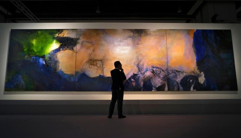 In this Wednesday, Sept. 26, 2018, file photo, a man stands in front of the largest-ever painting "Juin-Octobre 1985" by Chinese French artist Zao Wou-Ki during the Sotheby's auction press preview in Hong Kong. The painting expected to fetch US$45 million and will be on auction Sept. 30. (AP Photo/Vincent Yu, File)