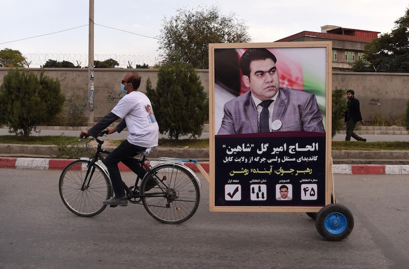 A supporter of candidate Alhaj Amir Gull Shaheen rides a bicycle with a trailer carrying his image along a street in Kabul. AFP