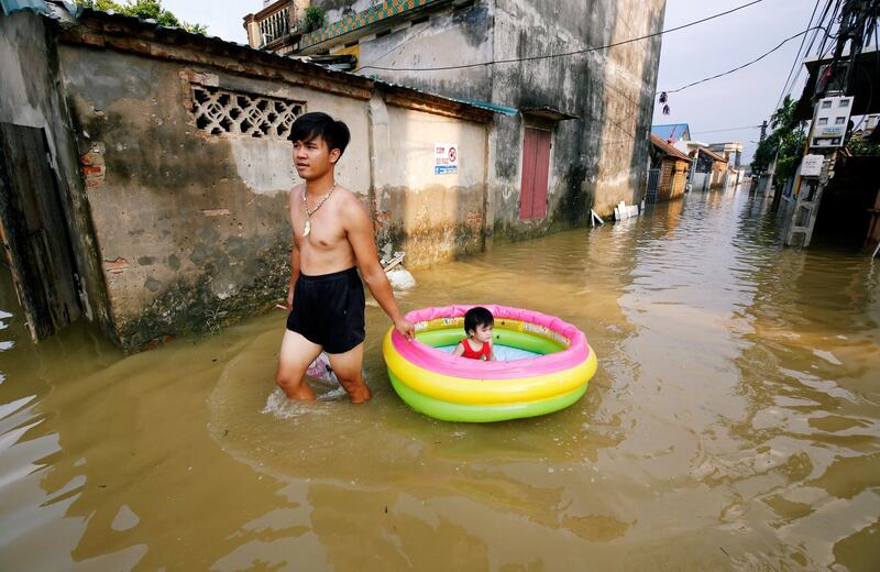 A man pulls an inflatable pool with his daughter on in a flooded village after heavy rainfall caused by tropical storm Son Tinh outside Hanoi, Vietnam. Kham/Reuters