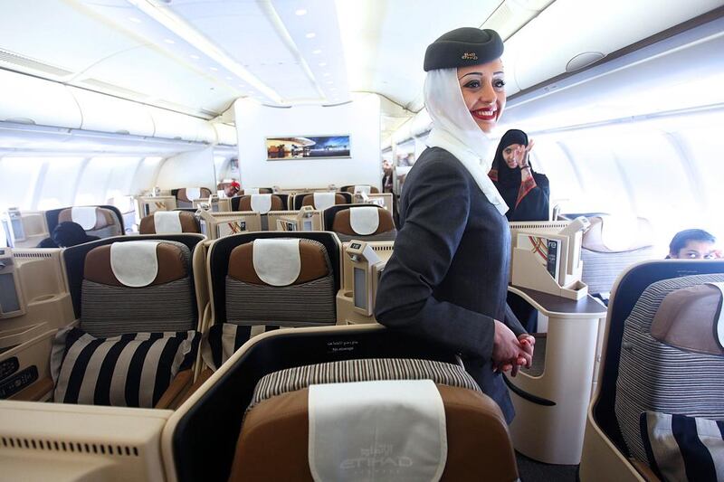 An Etihad flight attendant welcomes passengers on to an Etihad aircraft. The carrier is seeking apartments as it expands its staff. Sammy Dallal / The National