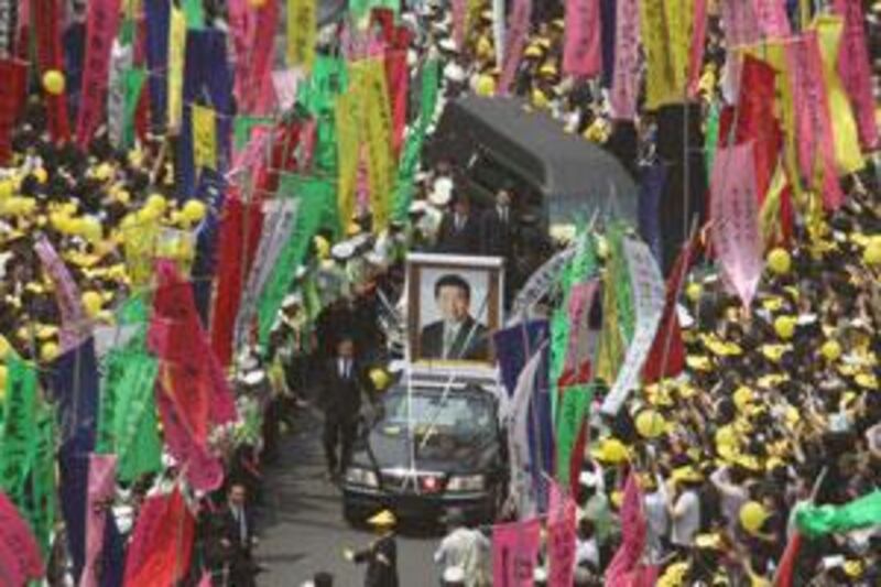 A huge portrait of Roh Moo-hyun, the late former South Korean president, leads the funeral hearse as it makes through a mammoth crowd.