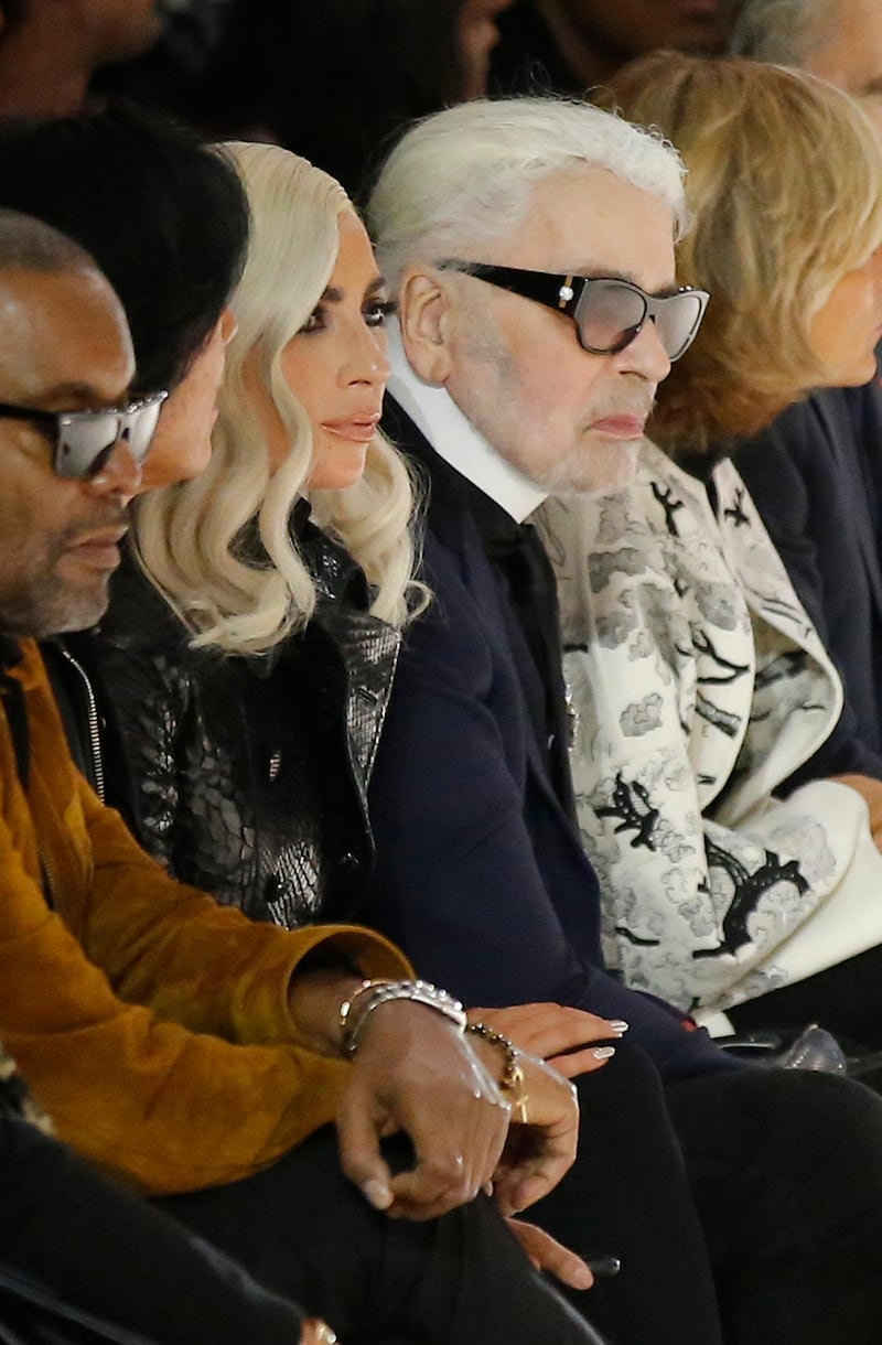 Singer Lady Gaga, centre, and designer Karl Lagerfeld, right, watch the Celine Spring/Summer 2019 ready to wear fashion collection presented in Paris, Friday, Sept. 28, 2018. (AP Photo/Michel Euler)
