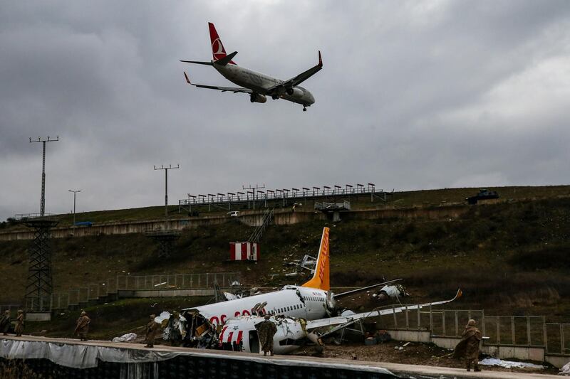 A plane descends to land, as soldiers guard the wreckage of a plane operated by Pegasus Airlines after it skidded Wednesday off the runway at Istanbul's Sabiha Gokcen Airport, in Istanbul. AP Photo