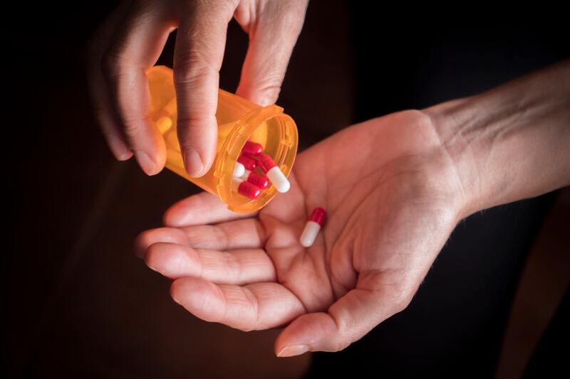 Man Removing Pills From Bottle. Getty Images