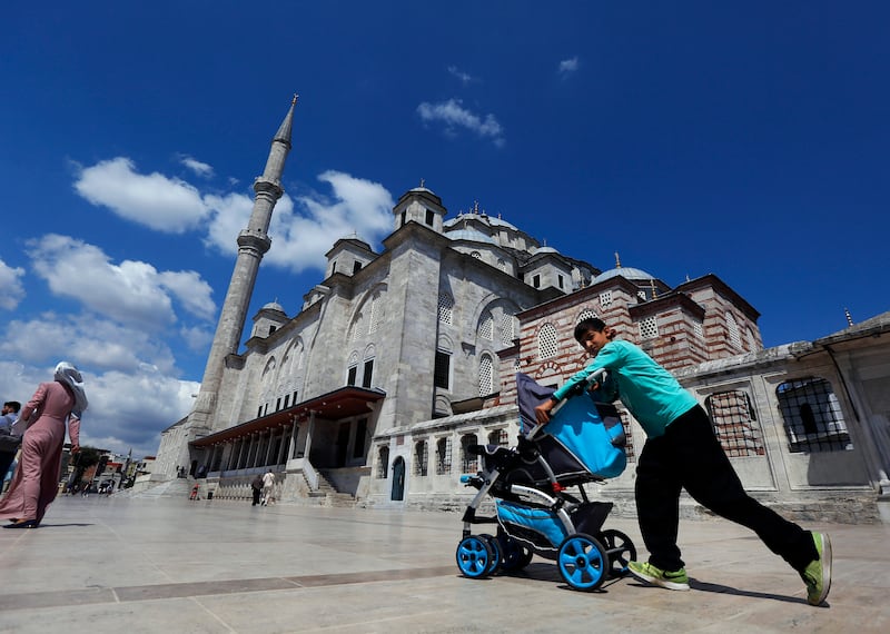 In this photo taken on Tuesday, Aug. 20, 2019, a Syrian boy pushes a pram past Fatih mosque in Istanbul. Syrians say Turkey has been detaining and forcing some Syrian refugees to return back to their country the past month. The expulsions reflect increasing anti-refugee sentiment in Turkey, which opened its doors to millions of Syrians fleeing their country's civil war. (AP Photo/Lefteris Pitarakis)