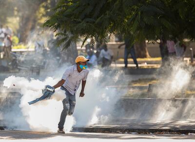 A demonstrator picks up a tear gas canister during protests against Haiti's President Jovenel Moise, in Port-au-Prince, Haiti February 8, 2021. REUTERS/Jeanty Junior Augustin
