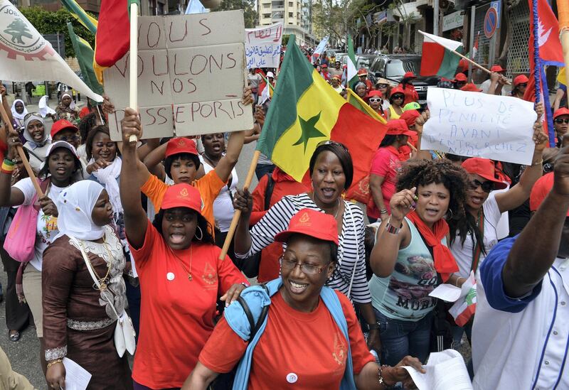 epa04731089 Migrant domestic workers carry placards with slogans such as: 'We want our passports' (L) and flags during a demonstration in Beirut, Lebanon, 03 May 2015. In an attempt to fight violence and abuse of mainly female domestic workers they launched their own union in Lebanon in January 2015 but are still waiting for official recognition by the country's Ministry of Labor, media reports say. More than 200,000 migrants from Sri Lanka, Ethiopia, the Philippines, Nepal, Senegal and other foreign countries work in Lebanon, many of them in the domestic service field, according to the reports.  EPA/WAEL HAMZEH *** Local Caption *** 51915616