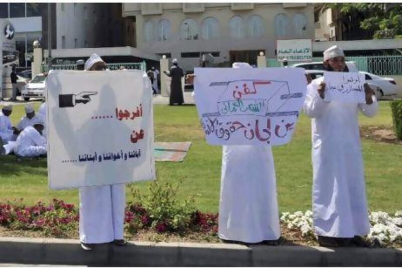 Protesters hold signs reading "Stop killing people in Sohar" and "Release our fathers, brothers, and sons" during a protest in front of the Public Prosecution building in Muscat.