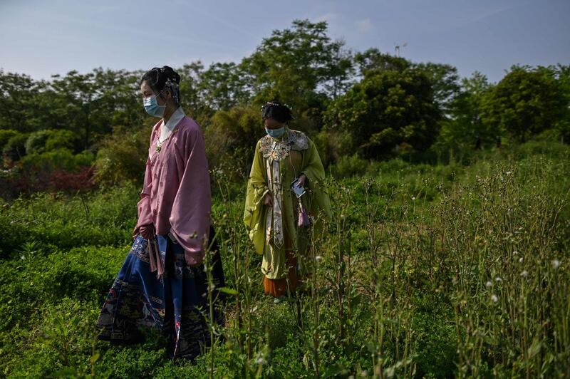 Young women in costumes of the Ming Dynasty and wearing face masks walk at Ma'snshan Forest Park in Wuhan, China's central Hubei province. AFP