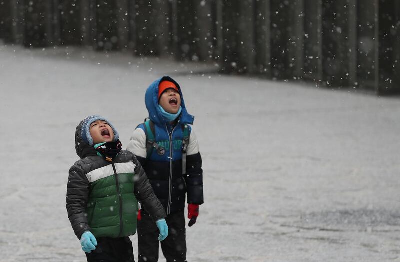 Foreign students try to catch snow in their mouths at Ewha Womans University in Seoul, South Korea. Yonhap / EPA