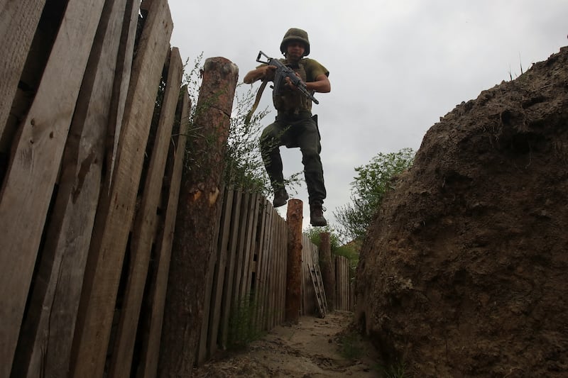 A member of the Ukrainian National Guard jumps into a trench at a position near a front line, in the Kharkiv region. Reuters
