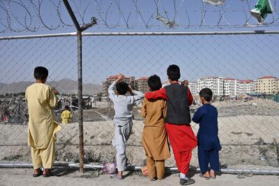 TOPSHOT - Children watch people at a camp for internally displaced people (IDP) where new apartment buildings are located in Kabul on June 21, 2021. / AFP / ADEK BERRY
