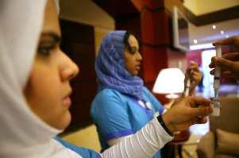 November 8, 2009 / Abu Dhabi / Fatima A. Al Shameri, left, and Mona Abdul Rahman both nurses with Seha prepare swine flu vaccines to be give out at the Emirates Center for Studies and Strategic Research in Abu Dhabi November 8, 2009.  (Sammy Dallal / The National)

 *** Local Caption ***  sd-110809-swineflu-08.jpg