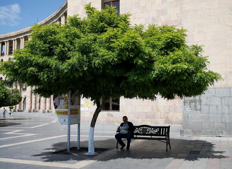 A man reads a newspaper under the shade of a tree in central Yerevan, Armenia. Gleb Garanich / Reuters