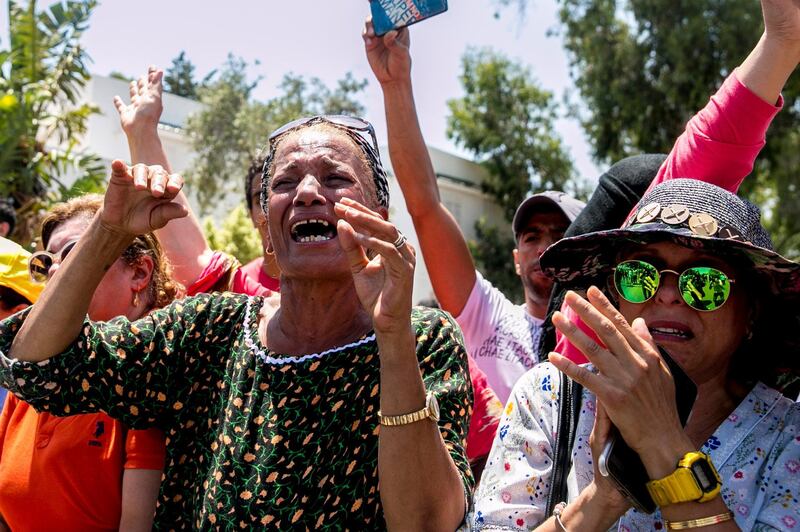 People react as the convoy carrying the body of Tunisian President Beji Caid Essebsi arrives at the presidential palace in Carthage, near Tunis, Tunisia, Friday, July 26, 2019. Tunisia is inviting world leaders to attend the funeral for its president who died in office and preparing a new election to replace him. The next election was originally set for Nov. 17, but is being rescheduled after President Beji Caid Essebsi died in office Thursday at 92. (AP Photo/Hassene Dridi)