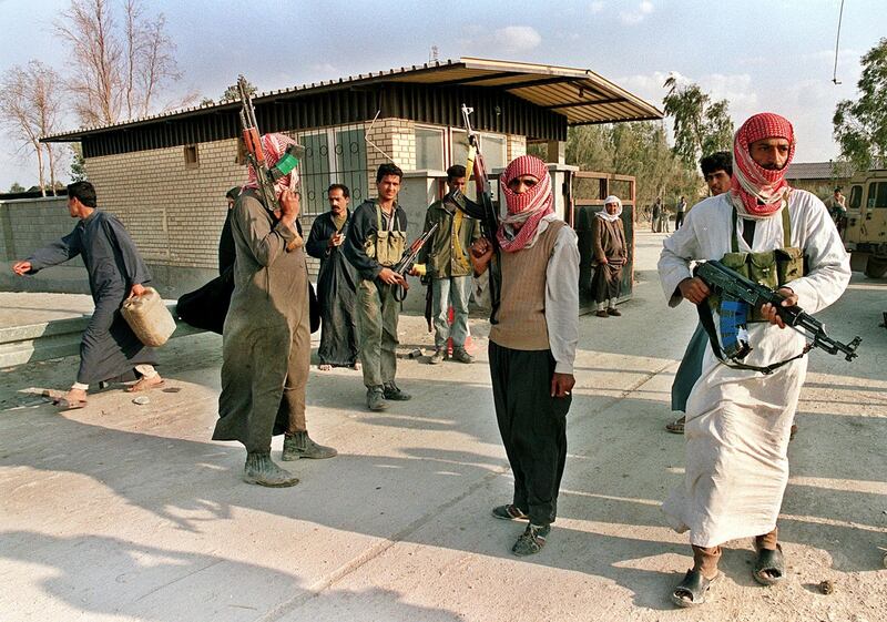 (FILES) Picture dated 27 March 1991 shows armed Iraqi rebels at their camp in the outskirts of the southern Iraqi city of Nassiriya. Iraqi security forces smashed Shiite protests killing at least 15 people, arresting almost 250 in Baghdad alone and restricting unrest 21 February to Nassiriya, the opposition said. The Supreme Council for Islamic Revolution in Iraq said the Iraqi army shelled areas of Nassiriya over which it lost control to rioters who attacked government buildings. (Photo by MANOOCHER DEGHATI / AFP FILES / AFP)