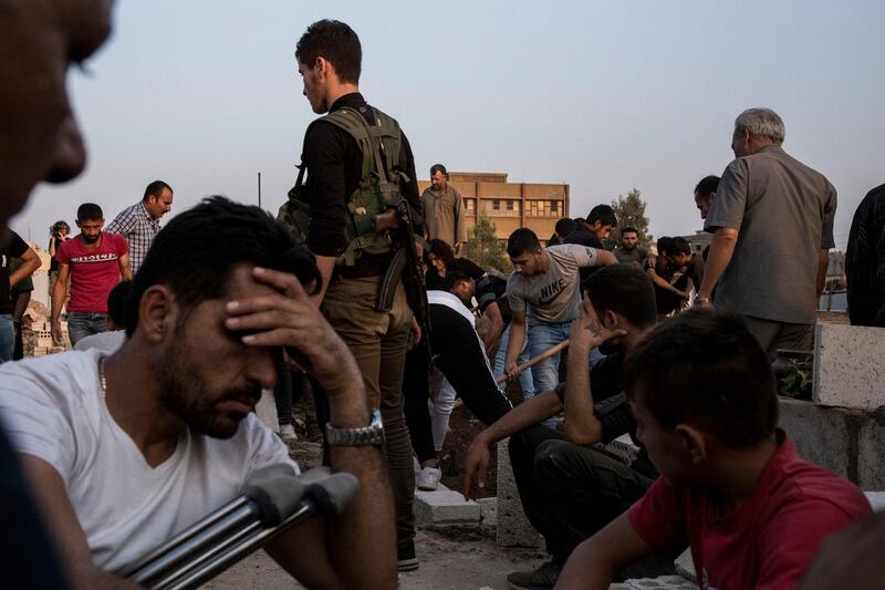 Syrians bury Syrian Democratic Forces fighters killed fighting Turkish advance in the Syrian town of Qamishli, Saturday, Oct. 12, 2019, Turkey's military says it has captured a key Syrian border town Ras al-Ayn under heavy bombardment in its most significant gain as its offensive against Kurdish fighters presses into its fourth day. (AP Photo/Baderkhan Ahmad)