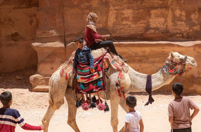 Children enjoy a ride on a camel at the reopened Petra archeological site. EPA