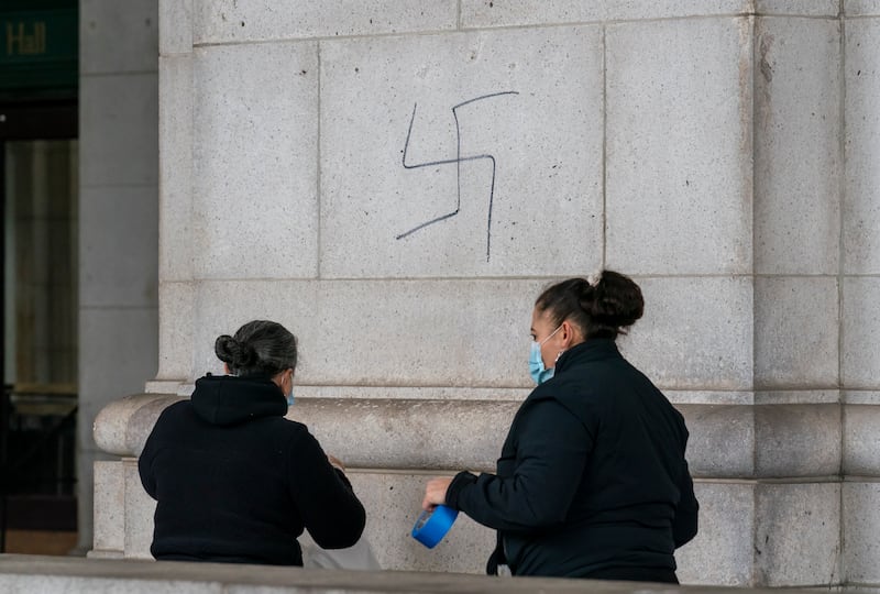 A cleaning crew prepares to cover hand-drawn swastikas. AP