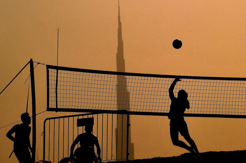 People play during a beach volleyball tournament in the Gulf emirate of Dubai on July 24, 2020, with the Burj Khalifa skyscraper seen in the background. After a painful four-month tourism shutdown that ended earlier in the month, Dubai is billing itself as a safe destination with the resources to ward off coronavirus. The emirate, which had 16.7 million visitors last year, had opened its doors to tourists despite global travel restrictions and the onset of the scorching Gulf summer in the hopes the sector will reboot before high season begins in the last quarter of 2020. / AFP / Karim SAHIB
