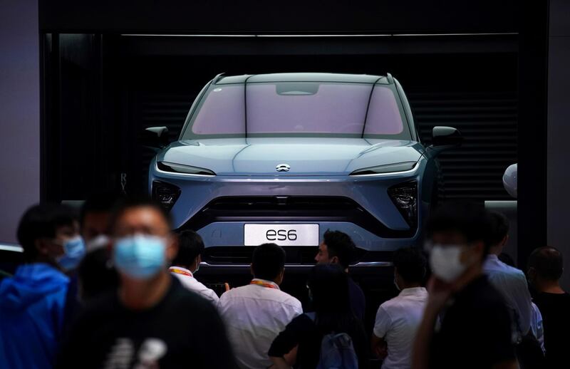FILE PHOTO: People wearing face masks look at a Nio ES6 EV car at the Beijing International Automotive Exhibition, China, Sept. 27, 2020. REUTERS/Tingshu Wang/File Photo