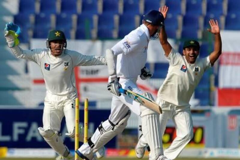 Pakistan's wicketkeeper Adnan Akmal (L) and Mohammad Hafeez (R) celebrate after English batsman Stuart Broad (C) was dismissed during the fourth day of the second Test match between Pakistan and England at Sheikh Zayed Stadium in Abu Dhabi on January 28, 2012. AFP PHOTO/LAKRUWAN WANNIARACHCHI
 *** Local Caption ***  746554-01-08.jpg