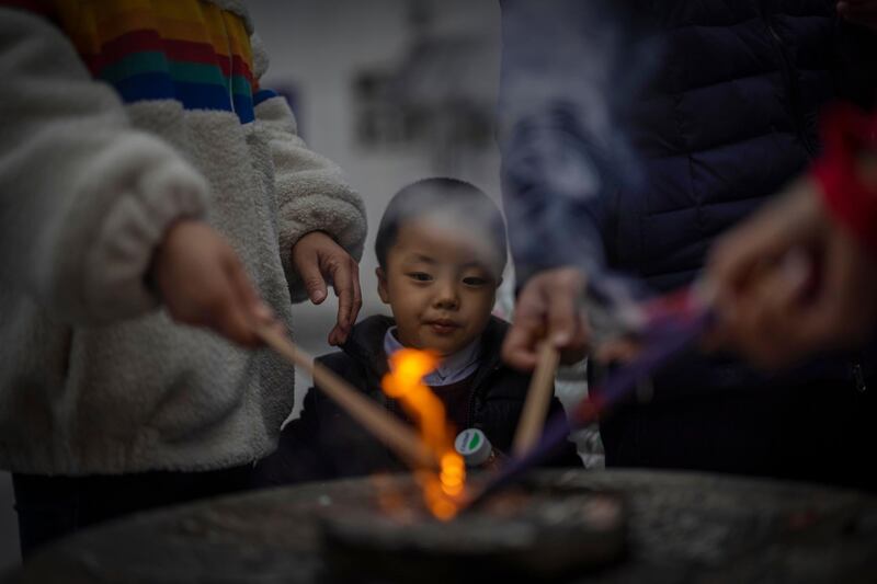 A boy looks while his parents are lighting incense sticks as offerings to their deceased ancestors in Jade Buddha Temple in Shanghai, China. EPA