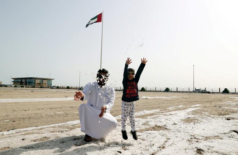 A boy and his father throw hail and sleet into the air following the unexpected deluge. Wam