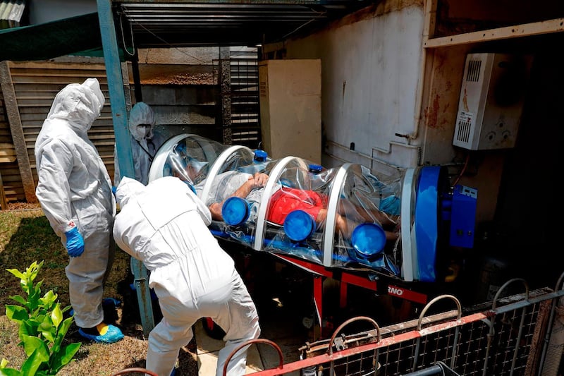 City of Tshwane's Special Infection Unit paramedics and a doctor load a man showing symptoms of Covid-19 into an isolation chamber in the north of Pretoria, South Africa. AFP