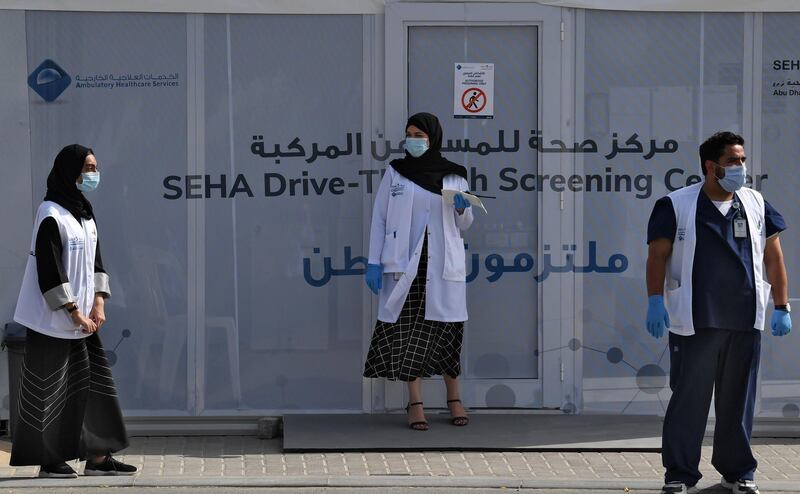 Medical volunteers wait outside a drive-through COVID-19 coronavirus testing centre in al-Khawaneej district of the gulf emirate of Dubai on April 9, 2020.  / AFP / KARIM SAHIB

