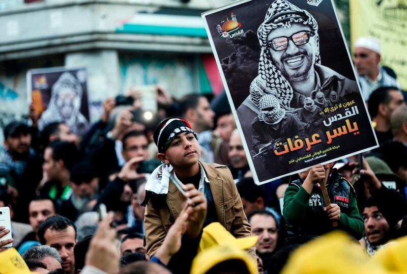 Supporters of the Fatah movement hold up a portrait of late Palestinian leader Yasser Arafat during a rally in Gaza City on December 31, 2017, marking the 53rd anniversary of the creation of the political party. / AFP PHOTO / MAHMUD HAMS