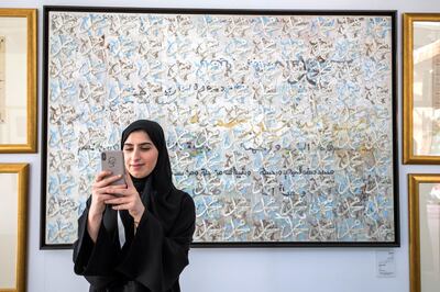 ABU DHABI, UNITED ARAB EMIRATES - A local woman taking photos of artwork at the Al Burda Festival, Shaping the Future of Islamic Art and Culture at Warehouse 421, Abu Dhabi.  Leslie Pableo for The National for Melissa Gronlund’s story