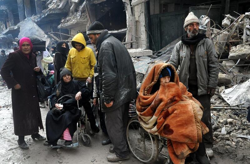 In this photo from February 4, 2014, Yarmouk residents wait at the gate of the camp to receive aid supplies from the United Nations. SANA, File/AP Photo