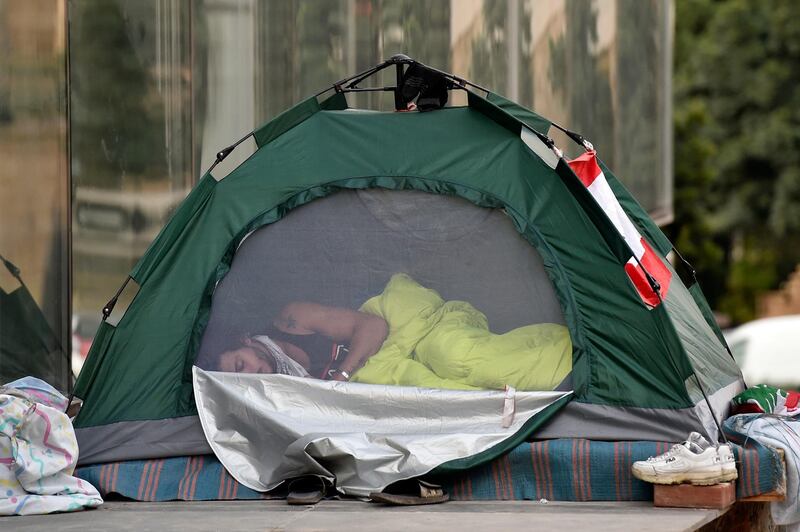 A protester sleeps in a tent as other protesters block the main highway during ongoing anti-government protests in Beirut, Lebanon.  EPA