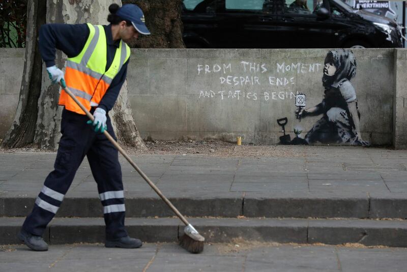 A road worker passes by an artwork which appears to be by street artist Banksy. PA via AP