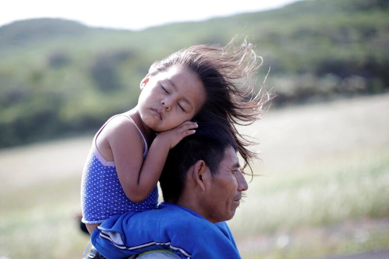 Rosendo Noviega, a 38-year-old migrant from Guatemala, part of a caravan of thousands from Central America en route to the United States, holds his daughter Belinda Izabel as he walks along the highway to Juchitan from Santiago Niltepec, Mexico, October 30, 2018. Reuters photographer Ueslei Marcelino: "They woke up early around 3am and Rosendo carried his daughter for hours alternating her position, from one arm to the other, from shoulders to back, from back to arms. We walked together, without food or water and Belinda gave into exhaustion and slept as we walked through the strong winds created by the wind farm at La Ventosa in Oaxaca. Minutes after this picture was taken a small truck passing by graciously heeded the request of other migrants to take the women and children to the next camp. Rosendo obtained the permission of the others to travel with his daughter and they drove to the next makeshift camp." REUTERS/Ueslei Marcelino  SEARCH "IMMIGRATION POY" FOR THIS STORY. SEARCH "REUTERS POY" FOR ALL BEST OF 2018 PACKAGES. TPX IMAGES OF THE DAY.