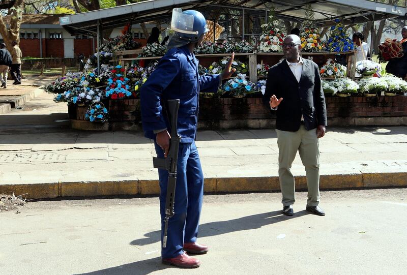 An armed riot policeman gestures to a pedestrian. AP Photo